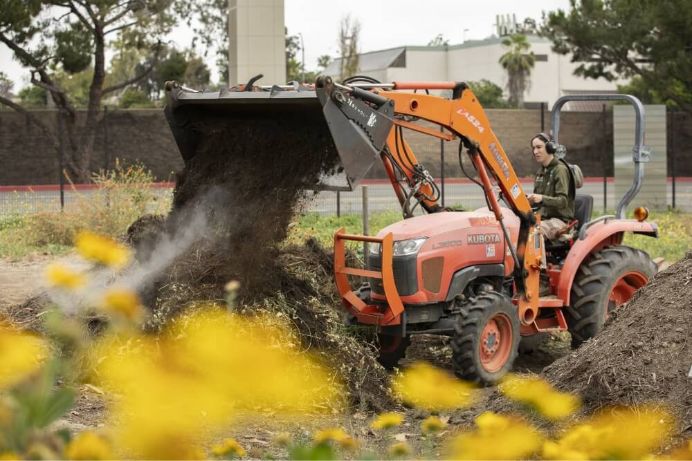 Amy Bulone operates a tractor to move compost